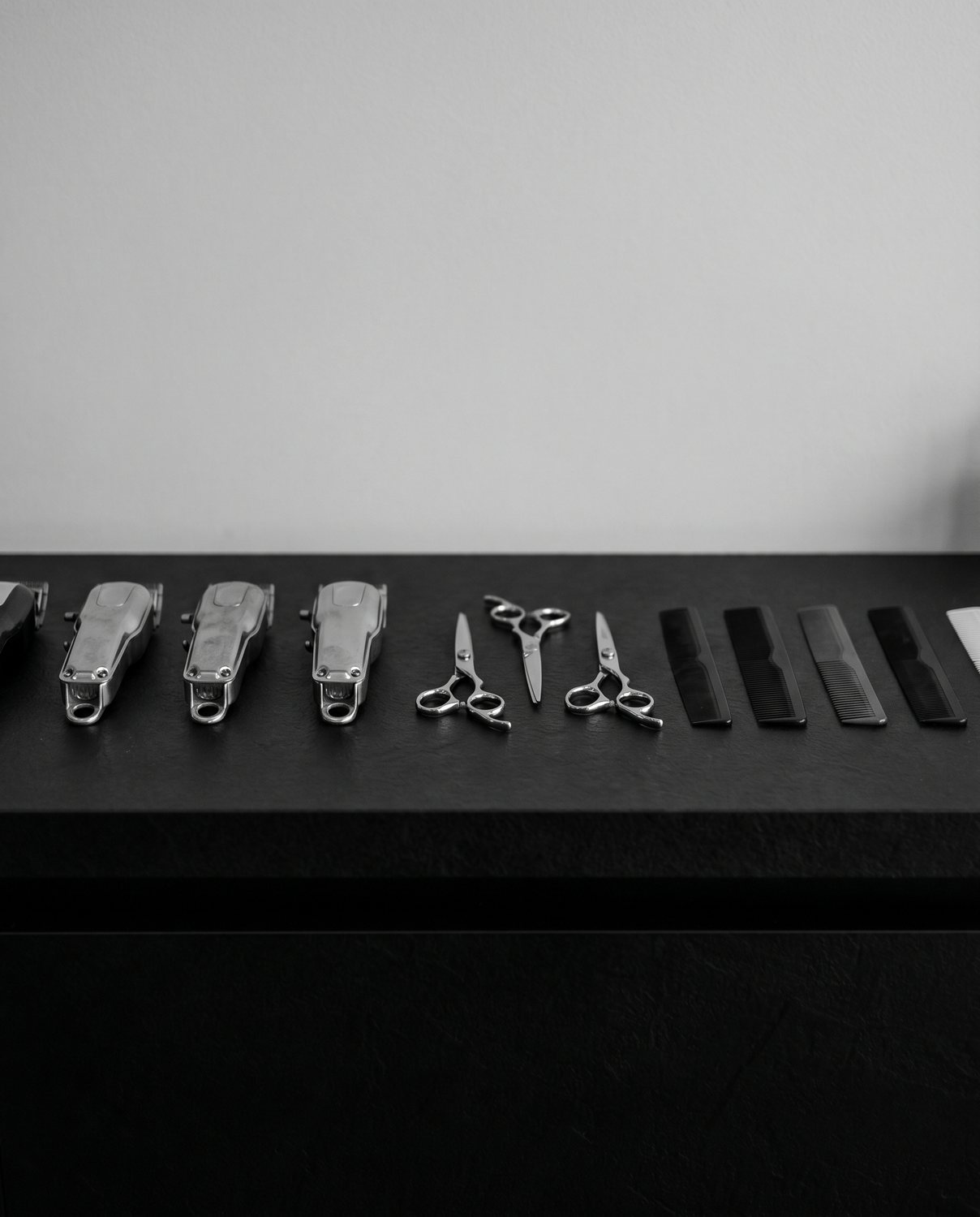 A neat row of clippers and combs on the backbar