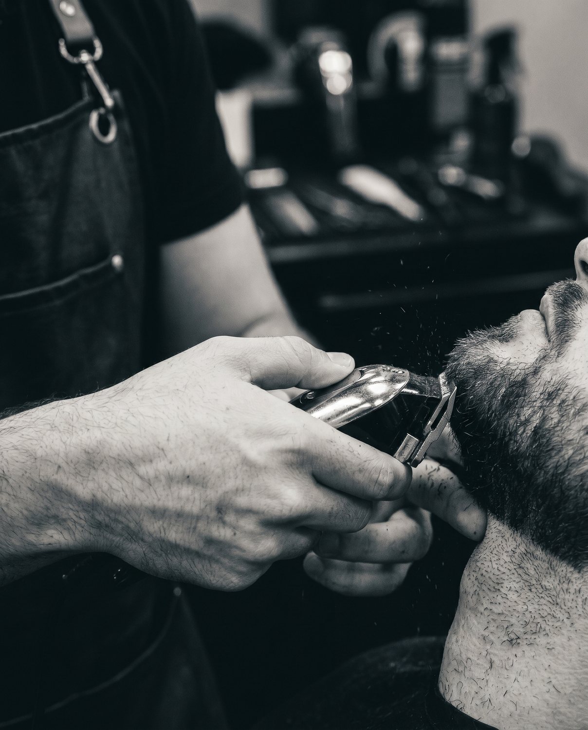A beard trim in progress, clippers in hand