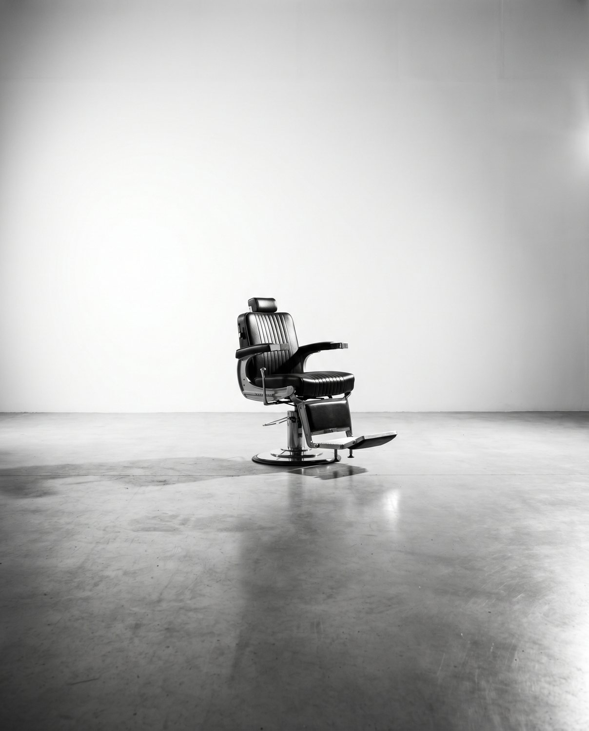 A single modern black barber chair against a white wall