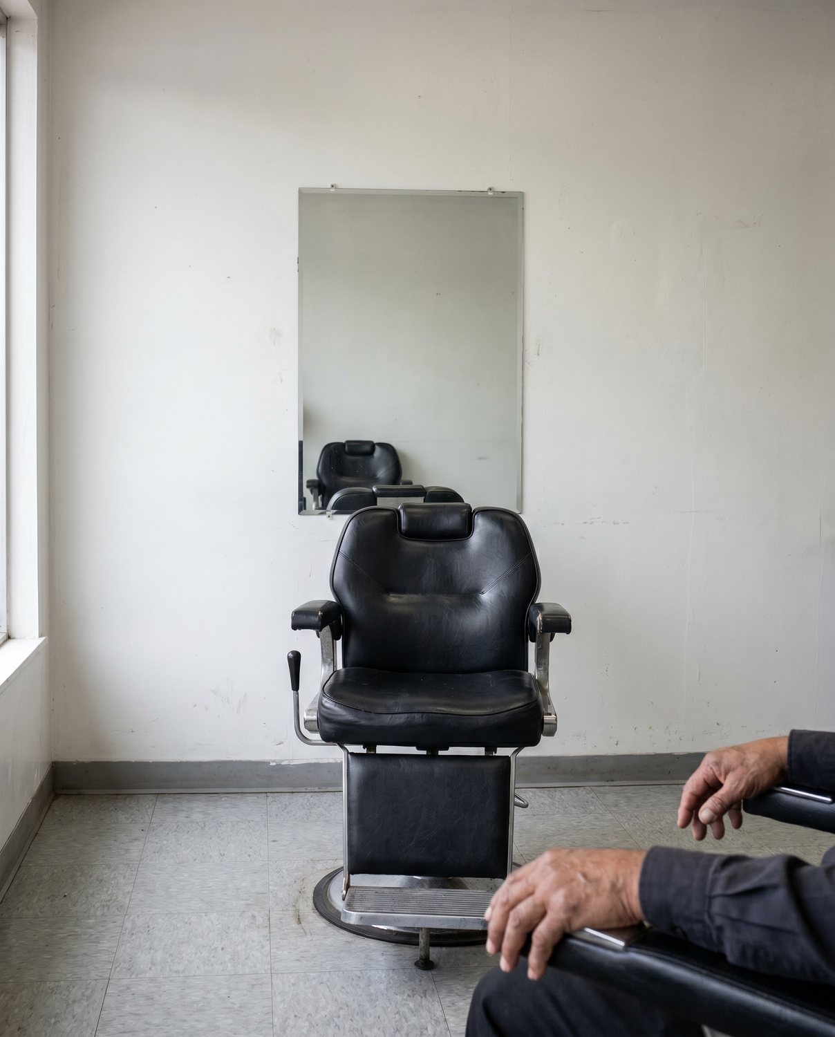 A single barber chair against a white wall