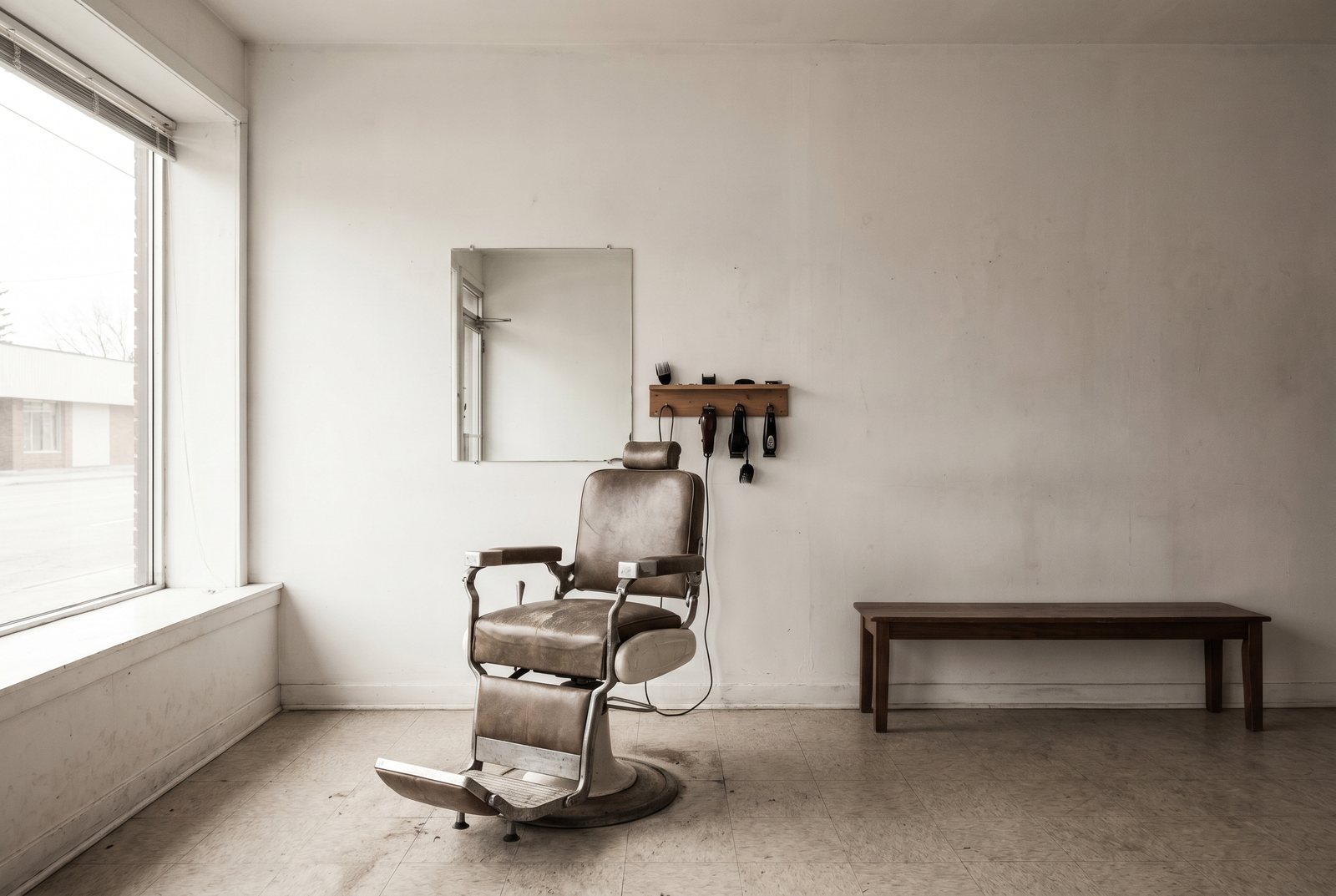 A small, plain barbershop interior, white walls and one clipper rack