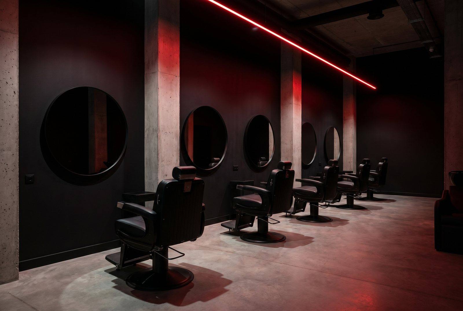 The blacked-out interior of Outlaw Barber Club under a red neon glow
