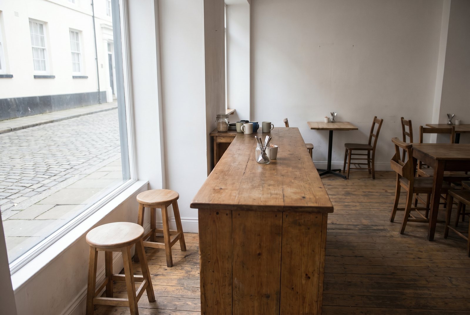 A small, plain cafe counter with one bench and a few stools