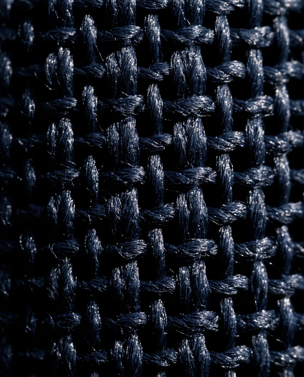 Macro of navy hopsack, the open basket weave catching points of light with black between the yarns