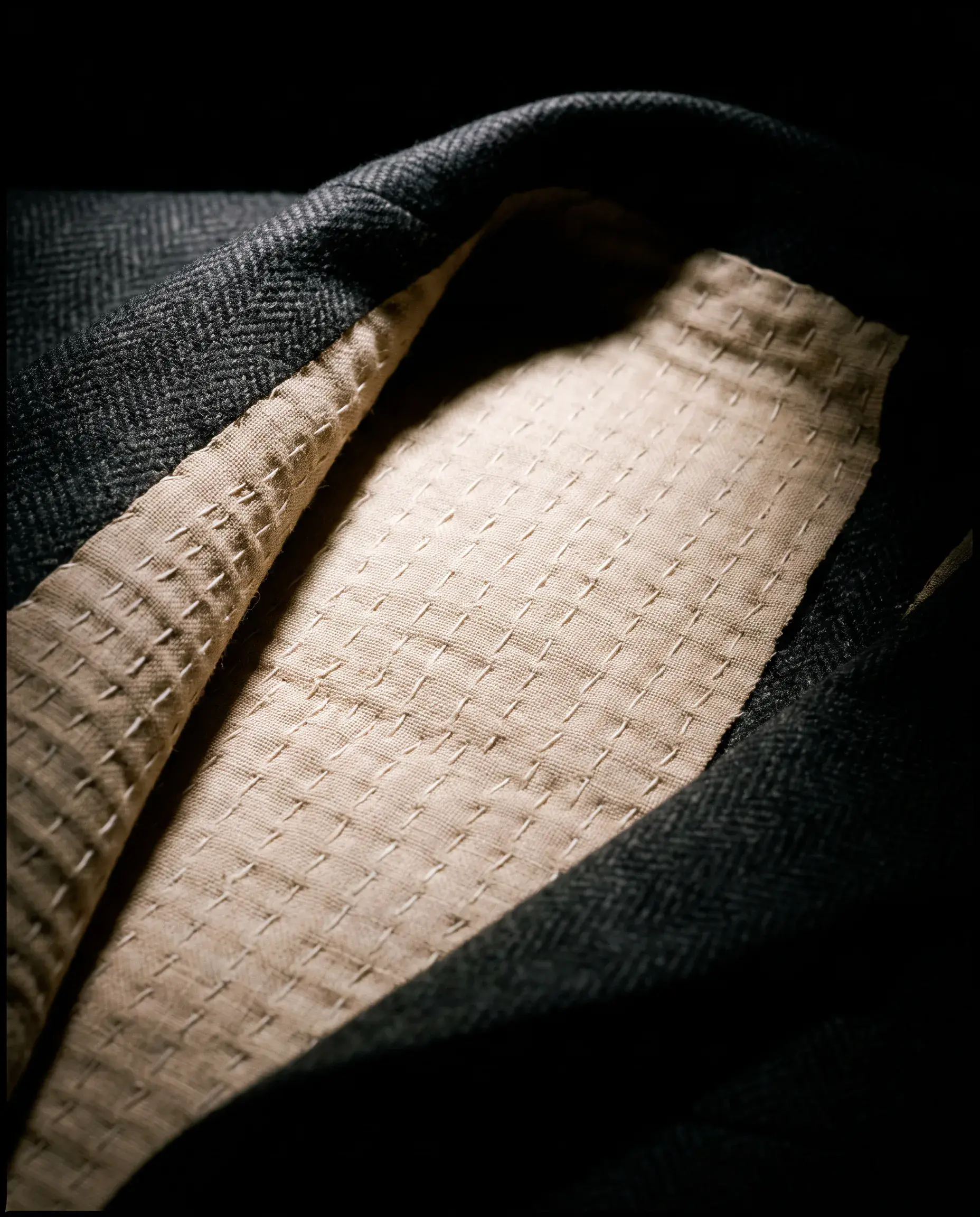 The jacket folded back to show the pale horsehair canvas inside, covered in dense parallel rows of hand pad stitching