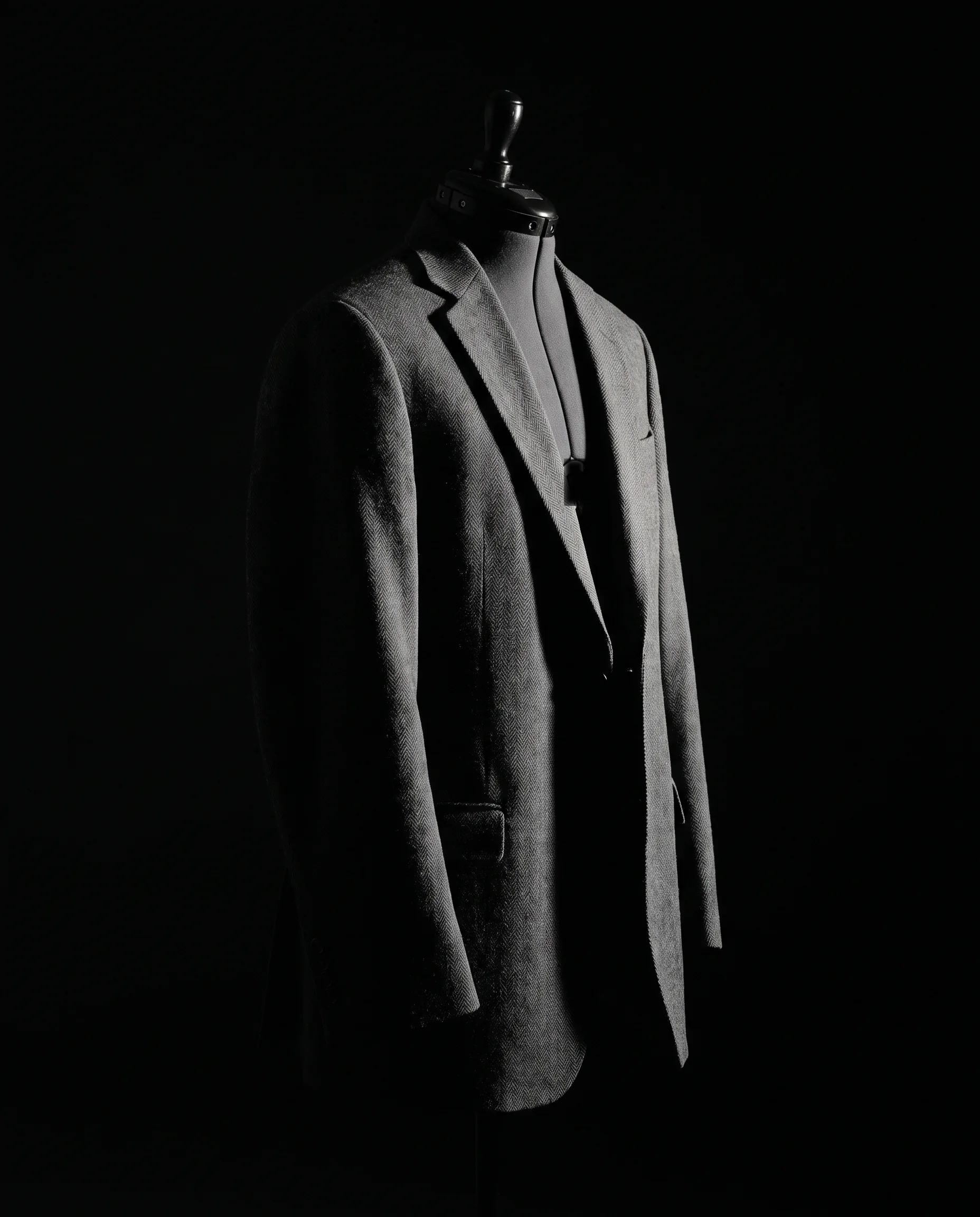 The whole jacket on the form at a three-quarter angle, light travelling down the fall of cloth from chest to skirt